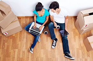 Couple sitting on floor looking at laptop